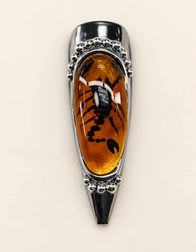 Silver pendant with oval amber stone featuring decorative metalwork setting