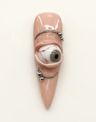Glossy beige sculptural art piece with pointed form and embedded eye detail, adorned with silver metallic bands