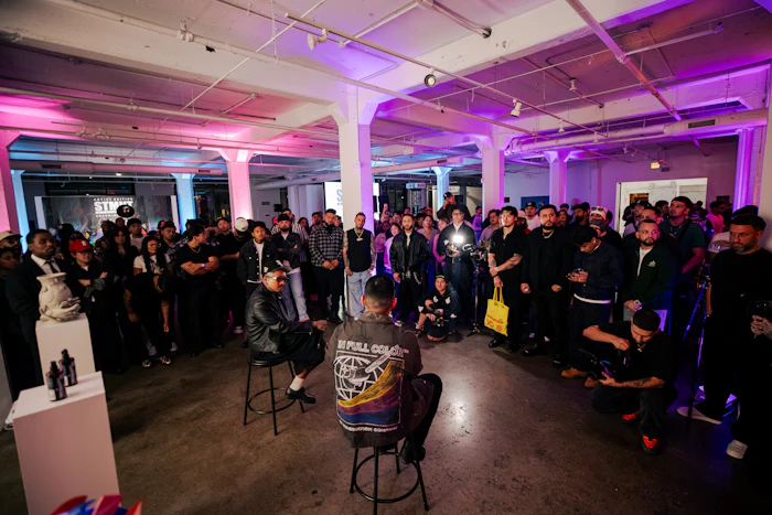 Large crowd of people gathered in a modern industrial venue with purple and pink ambient lighting during an event.